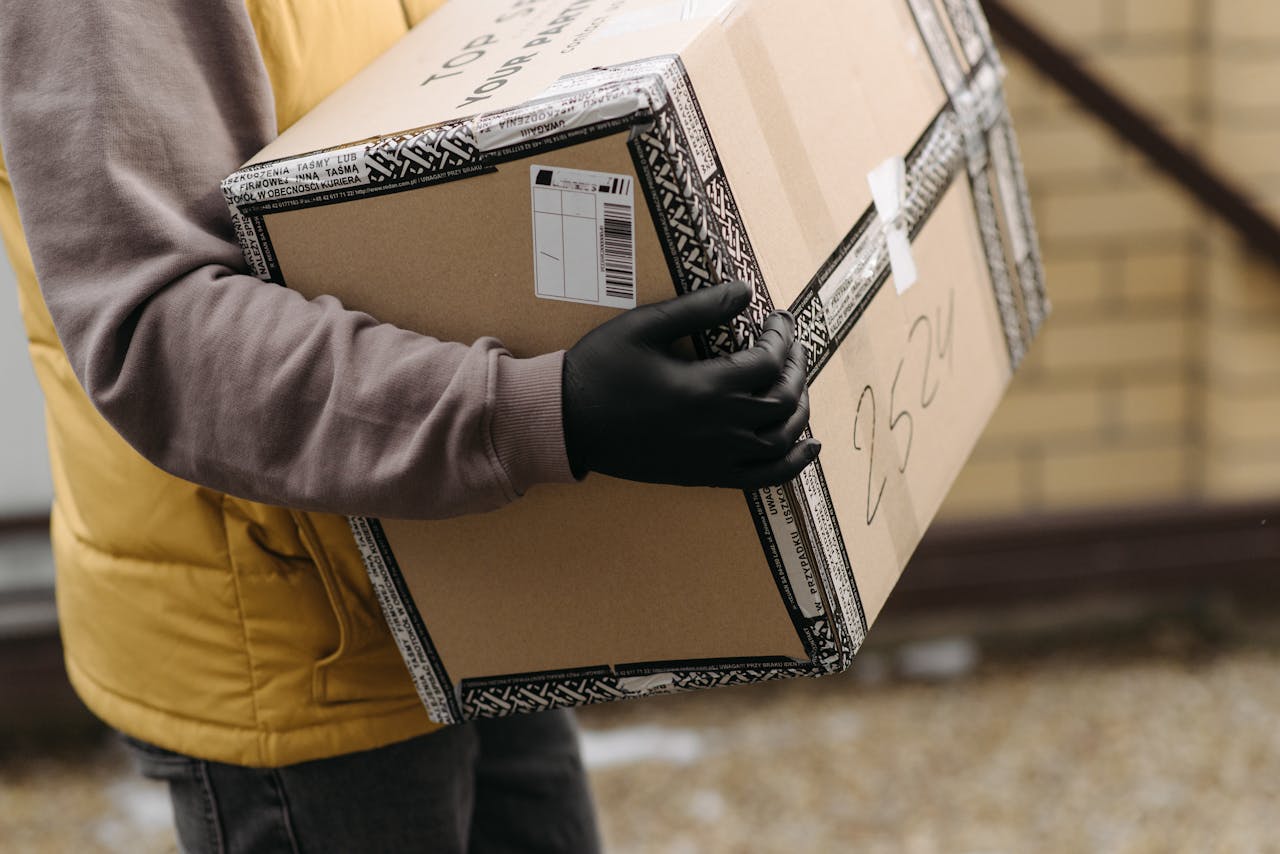 portfolio-04 Courier holding a package marked TOP PACKAGING wearing gloves for safe delivery.