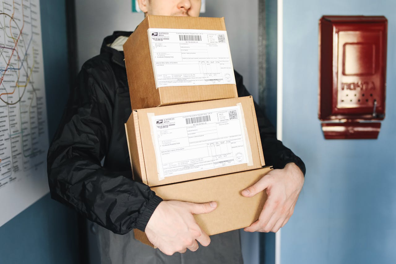 portfolio-03 Courier carrying stacked cardboard packages for delivery service indoors.